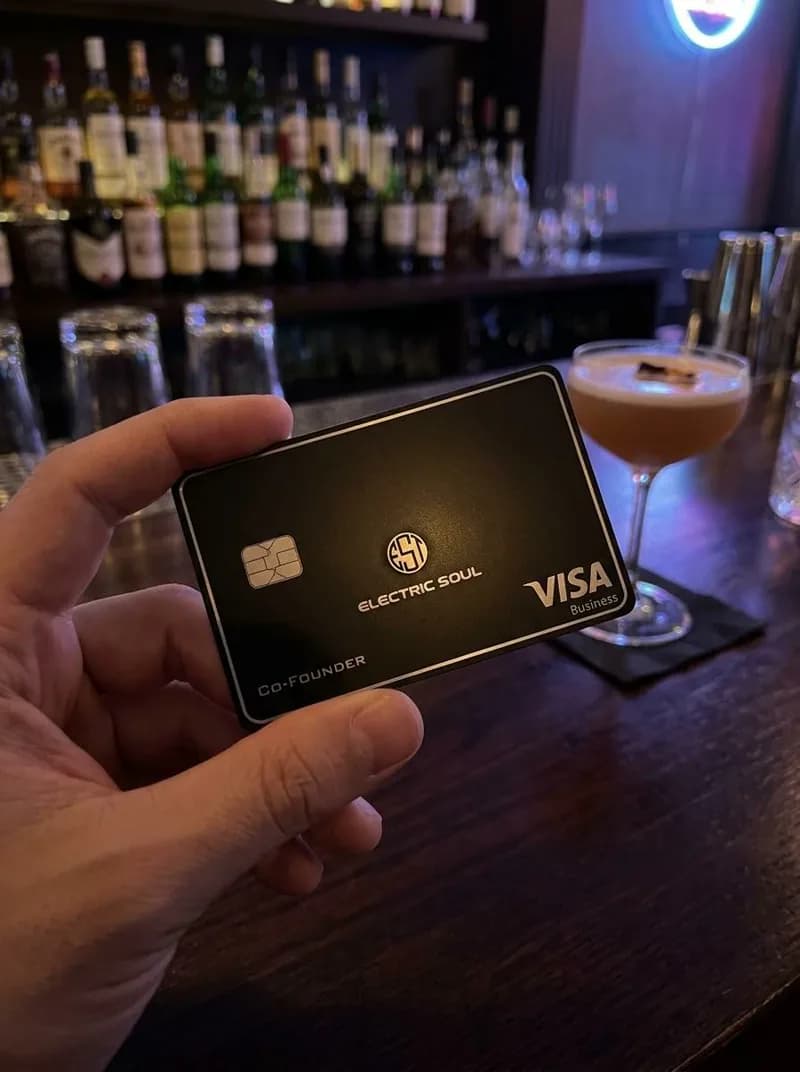Hand holding the Electric Soul card at a bar beside a cocktail