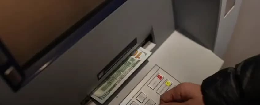 Hand withdrawing banknotes from an ATM