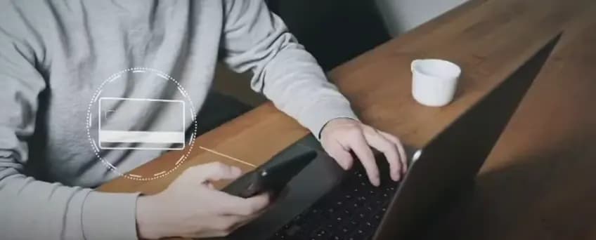 Person paying on a laptop with the card in hand